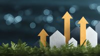 Growing real estate market concept with white paper houses and rising golden arrows on natural moss background with bokeh lights and copy space.