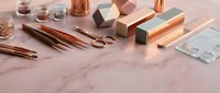 Elegant copper and rose gold office supplies arranged on marble surface for modern workspace design and stationery branding projects.