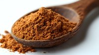 Ground cinnamon powder in wooden spoon macro close up view. Brown aromatic spice with selective focus on white background for cooking and baking.