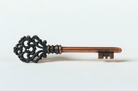 Vintage ornate skeleton key with black decorative bow and copper shaft isolated on white background, ready for design projects and creative use.