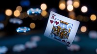 Playing card king of hearts floating against dark background with bokeh lights and poker chips, dramatic casino gambling composition for entertainment design.