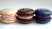 Three colorful French macarons with cream filling arranged on white background, sweet dessert pastry cookies for bakery menu design.