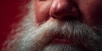 Close-up of senior Caucasian man with white beard and mustache against vibrant red background, showcasing aging facial features.