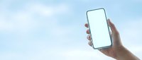 Hand holding smartphone with blank white screen against blue sky with clouds for mobile app mockup and digital technology presentation.