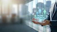 Businessman holding digital hologram with talent growth icons and symbols in modern office with city skyline view, representing career development and professional advancement strategy.
