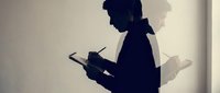 Silhouette of a person holding a tablet device against a white wall with natural light casting a shadow, suitable for technology, business, and digital innovation concepts.