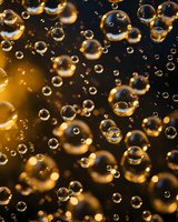 Transparent water drops and bubbles floating on dark background with golden light bokeh effect, macro photography style abstract composition.
