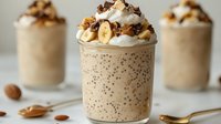 Creamy chia seed pudding topped with whipped cream, granola, and sliced banana in glass jars. Perfect for breakfast, dessert, or healthy snack recipes.
