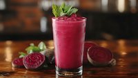 Fresh beetroot smoothie with mint garnish in glass on wooden table. Healthy detox drink with sliced beets for wellness lifestyle and nutrition concepts.