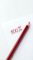Red pencil with 100 percent written on white paper background for business success and achievement concepts.