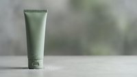 Green cosmetic tube with moisturizer, lotion, or skincare cream on white surface. Suitable for beauty, wellness, and product packaging design projects.