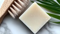 Natural soap bar with wooden brush and palm leaf on marble surface, eco-friendly bathroom accessories for sustainable lifestyle and personal care routine.