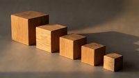 Wooden blocks in decreasing sizes arranged in a row, casting shadows on neutral surface. Suitable for business growth, progression, and organizational design projects.