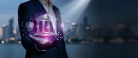 Businessman holding glowing digital bank building hologram with shield icons and network connections against blurred city skyline at night.