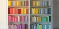Colorful bookshelf with books arranged in rainbow spectrum order from red to purple, creating an organized and visually appealing home library display.