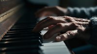 Elderly hand playing piano keys in dramatic lighting, capturing the emotion and artistry of a seasoned musician during a poignant performance.