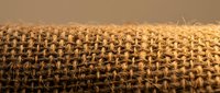 Natural burlap fabric texture with woven jute fibers in warm brown tones, perfect for rustic crafts, packaging design, and eco-friendly backgrounds.