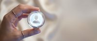 Close-up of hand holding glowing crystal sphere with user profile icon symbol, representing digital identity, personal data, customer focus, and business networking concepts.