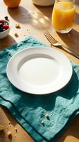 Overhead view of empty white plate on teal linen napkin with fresh orange juice, berries, and nuts on wooden table for breakfast or brunch styling.