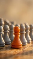 Orange chess pawn standing out among white pawns on wooden board, symbolizing leadership, uniqueness, individuality and competitive strategy for business concepts.