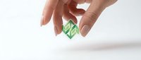 Hand holding a small green leaf logo cube, symbolizing eco-friendly business, sustainability, and environmental branding concepts on white background.