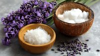 Organic coconut oil and salt with fresh lavender flowers on stone background for natural skincare and aromatherapy spa treatments.