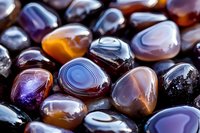 Polished agate stones in rich purple, orange, and blue tones with natural banding patterns and smooth surfaces, displaying vibrant mineral formations and translucent layers.