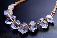 Elegant crystal quartz necklace with raw gemstone beads on gold chain against dark background for luxury jewelry design and fashion accessories.