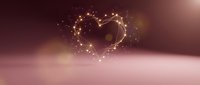 Golden heart shape made of glowing particles and light trails floating above soft pink surface with warm bokeh background for romantic designs.
