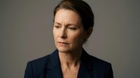 Middle-aged woman with brown hair wearing dark blazer, displaying serious expression against neutral gray background for corporate and professional use.