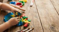 Child hands playing with colorful educational toys on wooden floor. Early childhood development and learning through play activities at home.