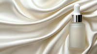 Frosted glass dropper bottle on luxurious ivory silk fabric background with elegant folds and soft shadows. Premium cosmetic packaging mockup for skincare products.