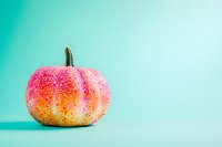 Pink and gold glittery decorative pumpkin on mint green background with copy space, modern festive autumn decor for seasonal celebrations.
