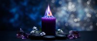 Purple candle with flame surrounded by amethyst crystals and small white flowers on dark surface with bokeh lights background for meditation and relaxation.