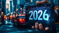 Futuristic digital tablet displaying year 2026 with financial graph against blurred urban cityscape background with bokeh lights and traffic at dusk.