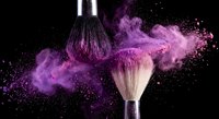 Makeup brush with purple powder explosion on black background for cosmetic and beauty industry advertising campaigns.