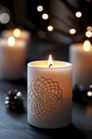 Elegant white candle with decorative mandala pattern glowing warmly among bokeh lights creating cozy atmospheric home decor ambiance.