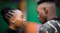 Young African couple facing each other in profile against green background, woman with braided updo hairstyle and man in camouflage shirt with fade haircut.