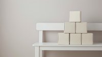 Stacked wooden blocks on white shelf against neutral wall, representing growth, progress, and business strategy for corporate design projects.