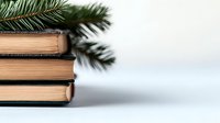 Stack of vintage books with pine branches on light background, creating cozy winter holiday atmosphere. Selective focus captures nostalgic mood for seasonal designs.