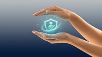 Hands protecting glowing digital shield with person icon, representing cybersecurity, data protection, and safe online privacy for business and technology concepts.