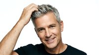 Middle-aged man with gray hair and light skin tone wearing black casual shirt, smiling at camera with hand touching head in relaxed pose for portrait and lifestyle use.