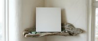 Blank white canvas on rustic driftwood shelf against textured wall, minimalist home decor mockup for artwork display and interior design projects.