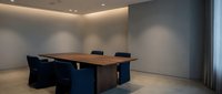 Modern minimalist conference room with wooden table and blue chairs in contemporary office space for business meetings and corporate presentations.
