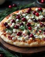 Gourmet pizza topped with fresh cranberries, goat cheese and rosemary herbs on wooden board. Festive holiday appetizer or main dish for seasonal dining.