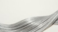Silky strands of long gray hair flowing gracefully against a neutral background, showcasing texture and movement for haircare, beauty, and wellness design projects.