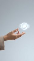 Hand reaching toward glowing white circular hologram symbol on gray background representing digital technology and futuristic interface interaction.