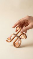 Hand holding copper sculptural fidget toy with curved loops and spheres against neutral beige background for stress relief and sensory play.