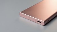 Rose gold external battery power bank with USB-C port for charging mobile devices and electronics on gray background.