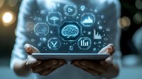 Digital technology icons floating above tablet device held by hands, glowing brain symbol with data analytics and cloud computing elements on dark background.